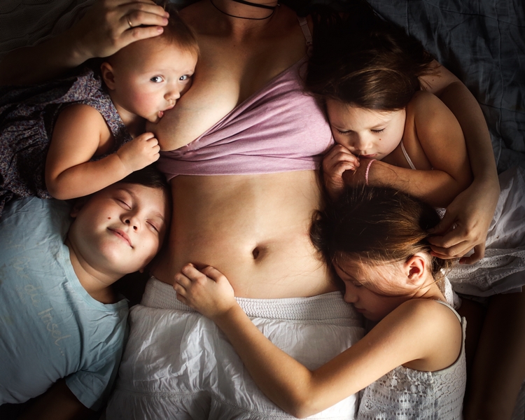 femme qui allaite son bébé avec ses enfants autour
