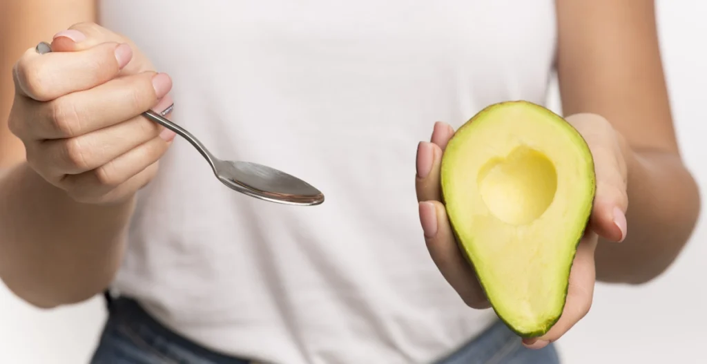Une personne qui tient un demi avocat dans une main et une cuillère dans une autre