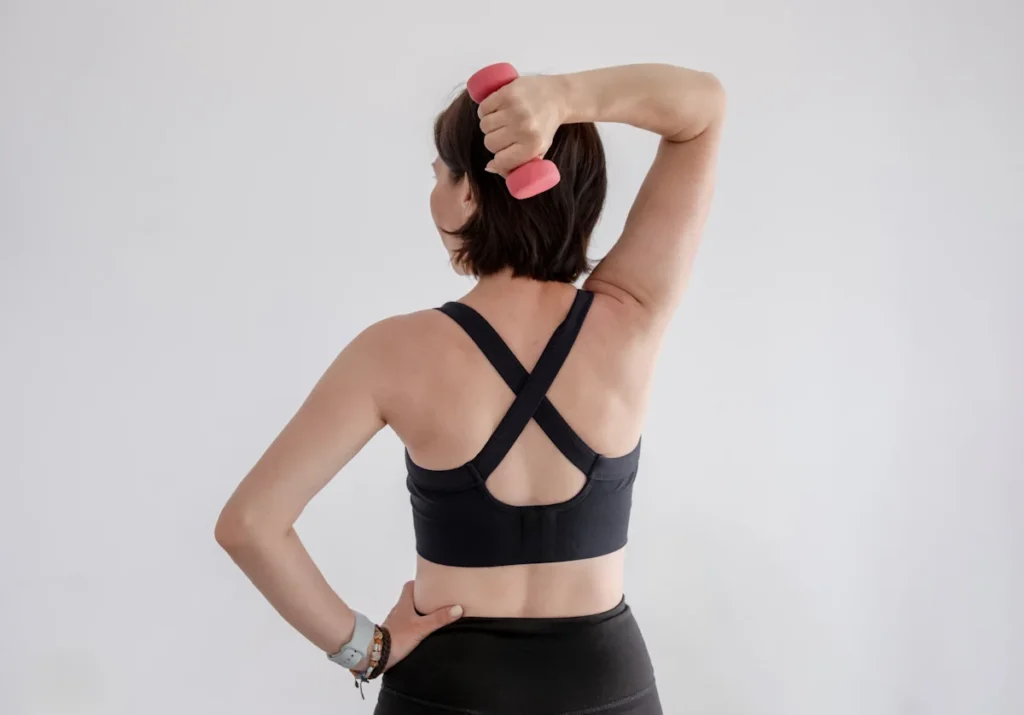 Une femme qui tient un poids dans sa main pour le balancer vers son dos en tenant ses hanche de l'autre main