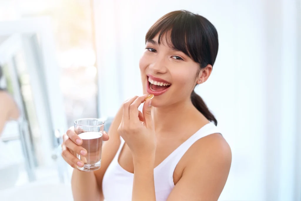 Une femme qui prend une pilule avec un verre d'eau