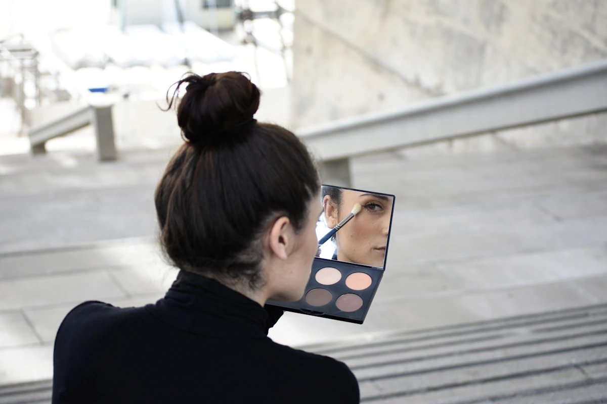 Une femme qui se maquille avec une palette de fard à paupière