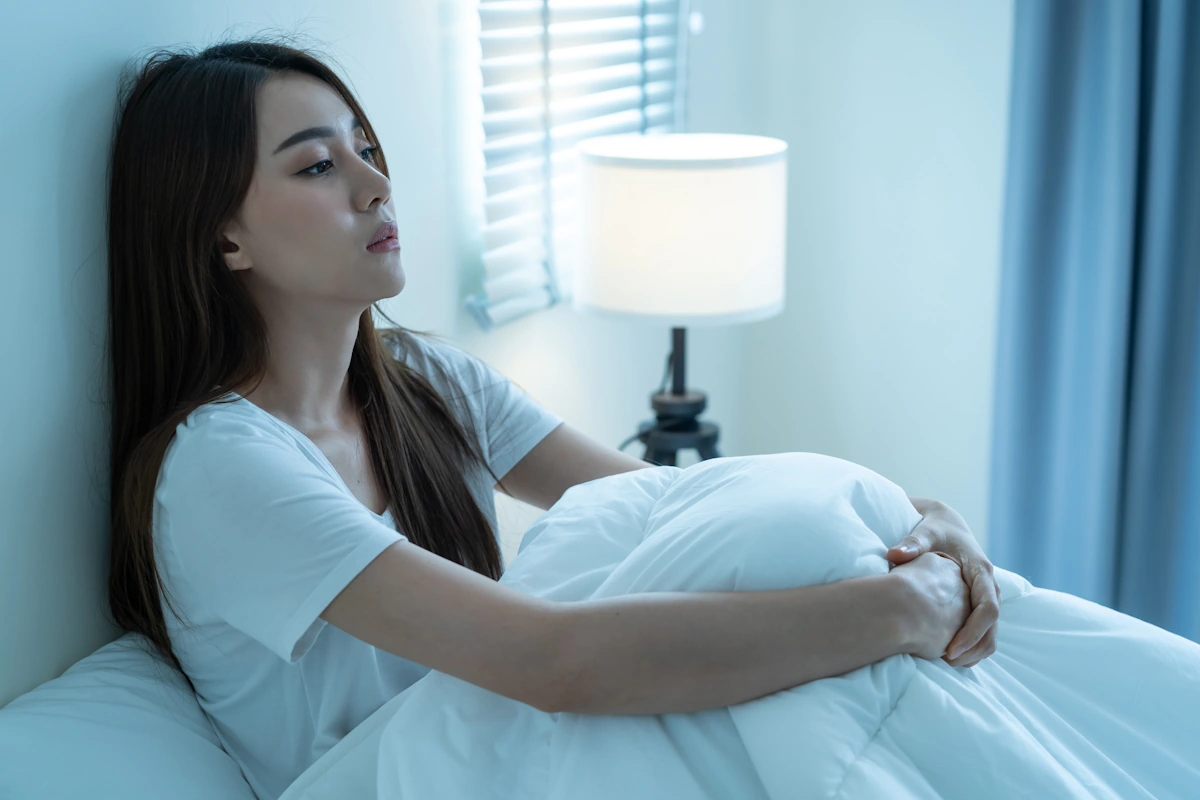Une femme assise dans son lit avec les yeux ouverts