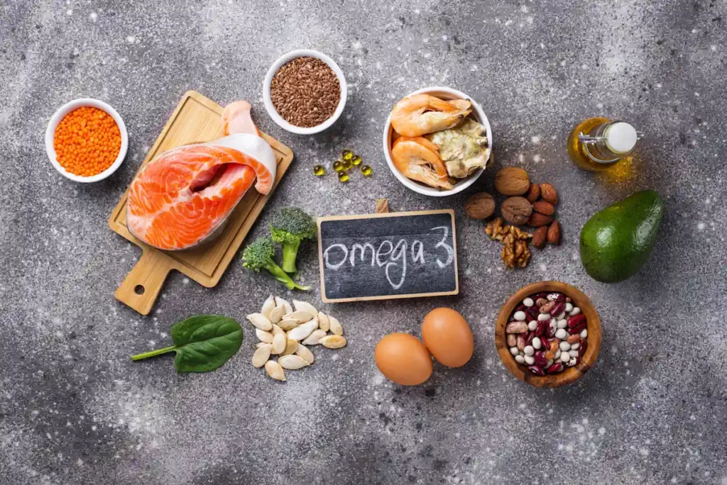 Différents aliments posés sur une surface grise avec le mot oméga 3 écrit sur une ardoise au milieu