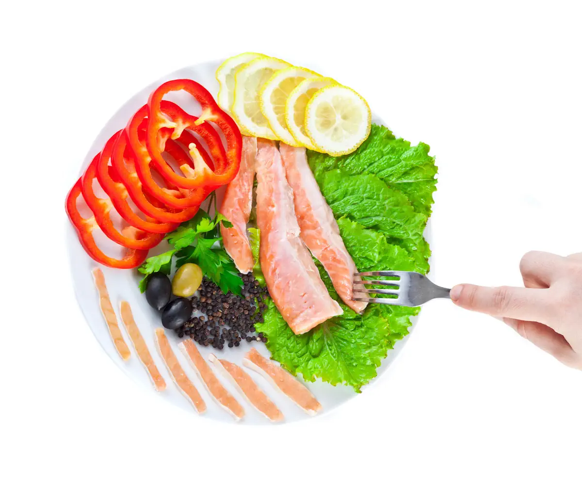 Une assiette de poisson avec de la salade, du tomate et du citron