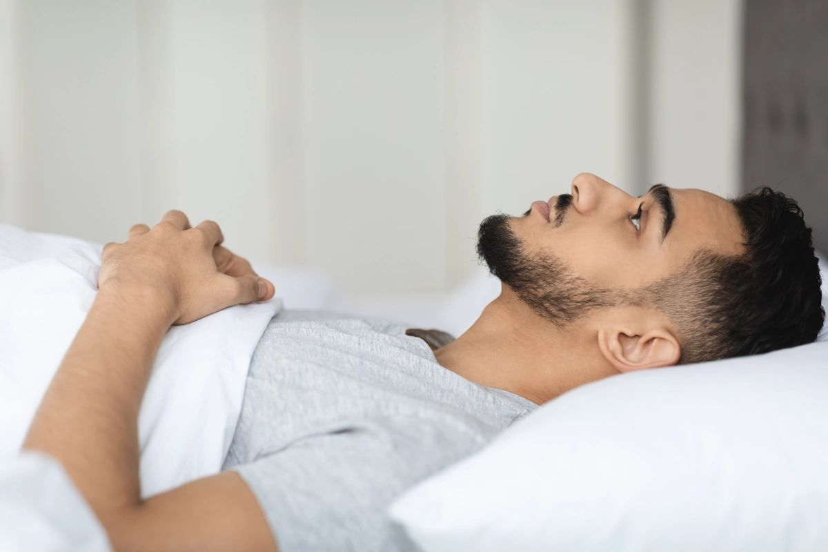 Un homme allongé dans un lit avec les yeux ouverts